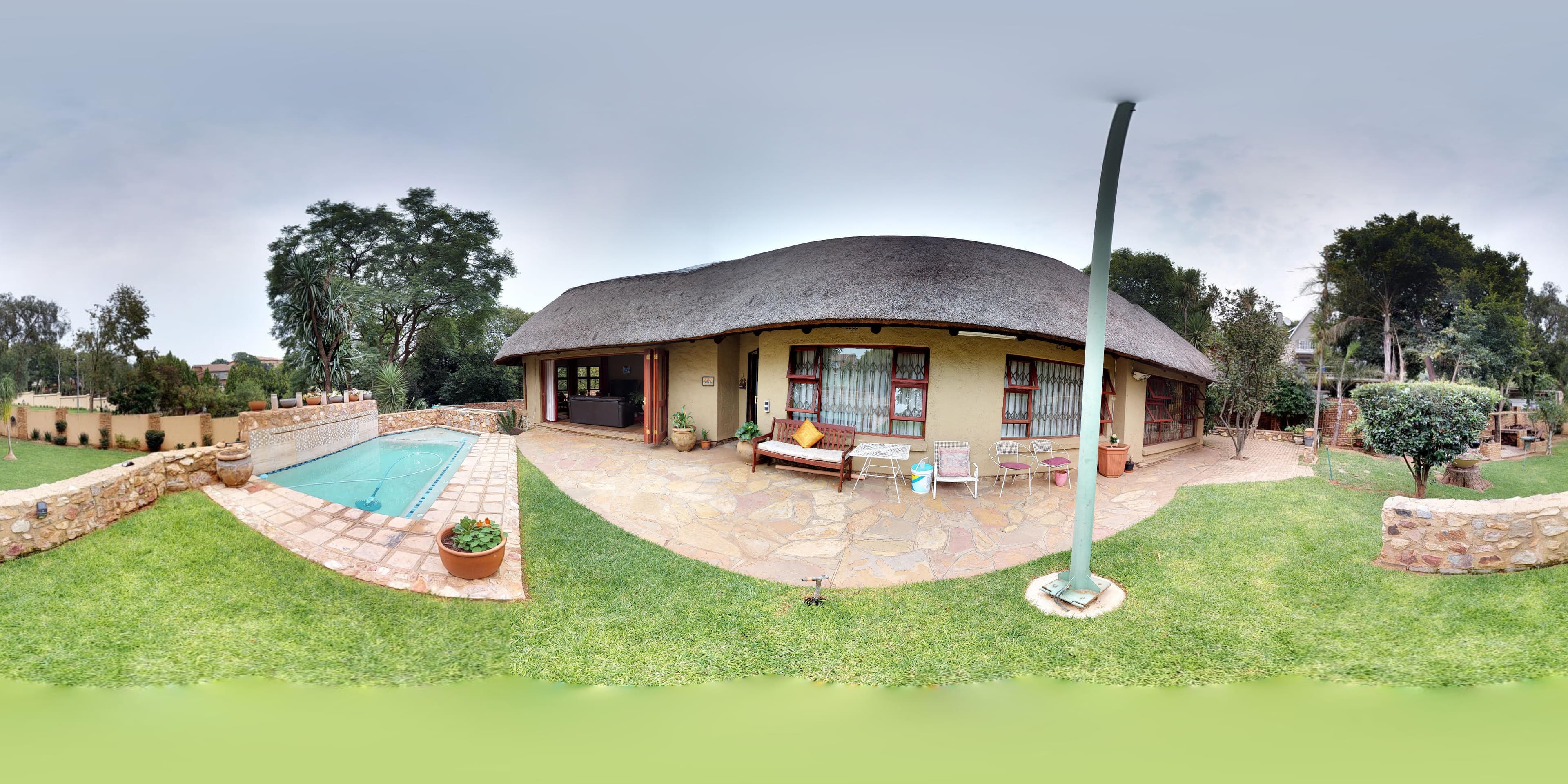 A panoramic view of a property, garden and swimming pool