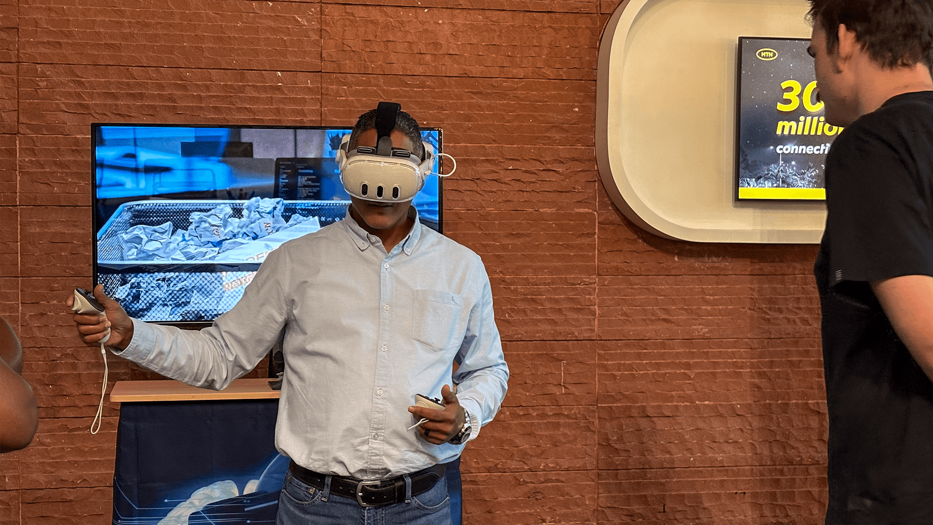 A participant using VR controllers in front of an event screen