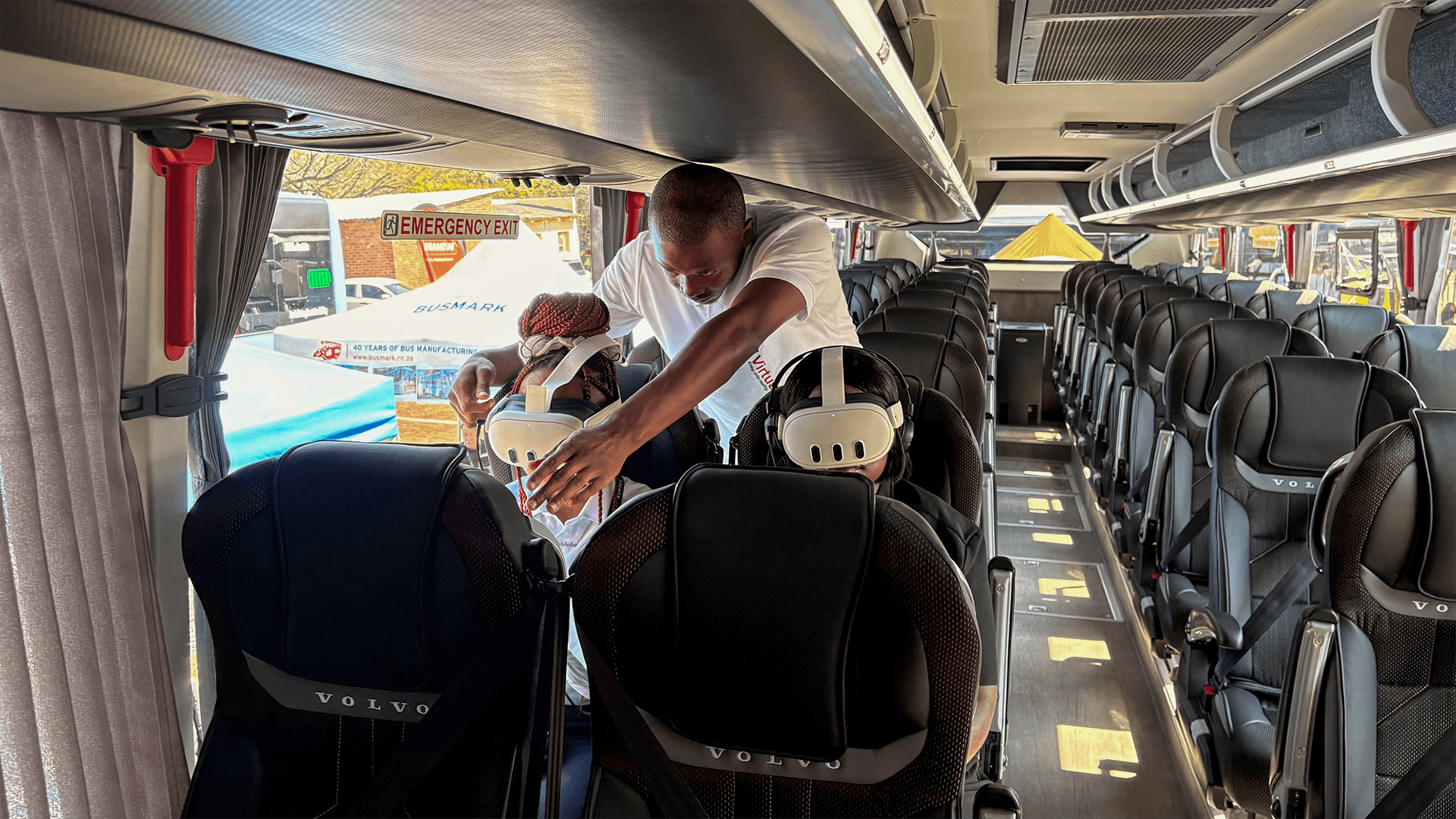 A team member helping seated guests with VR headsets on a coach