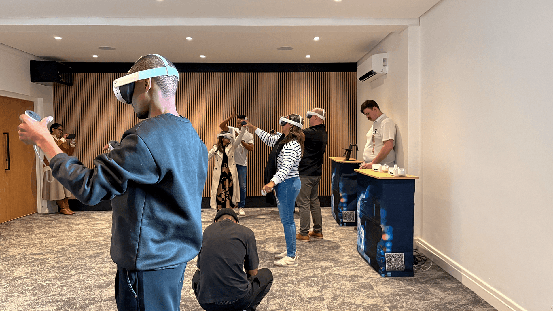 Participants using VR headsets and controllers in an indoor event space
