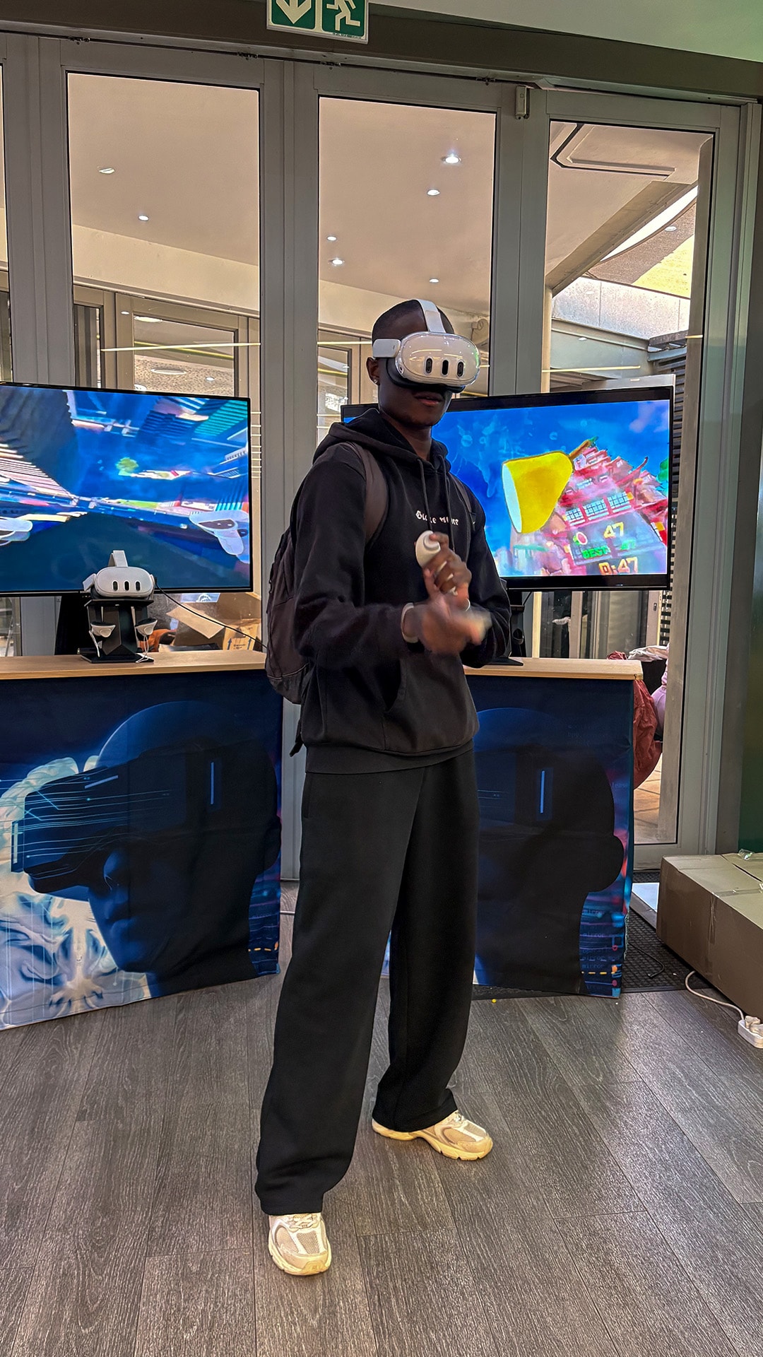 A participant using VR controllers in front of event screens