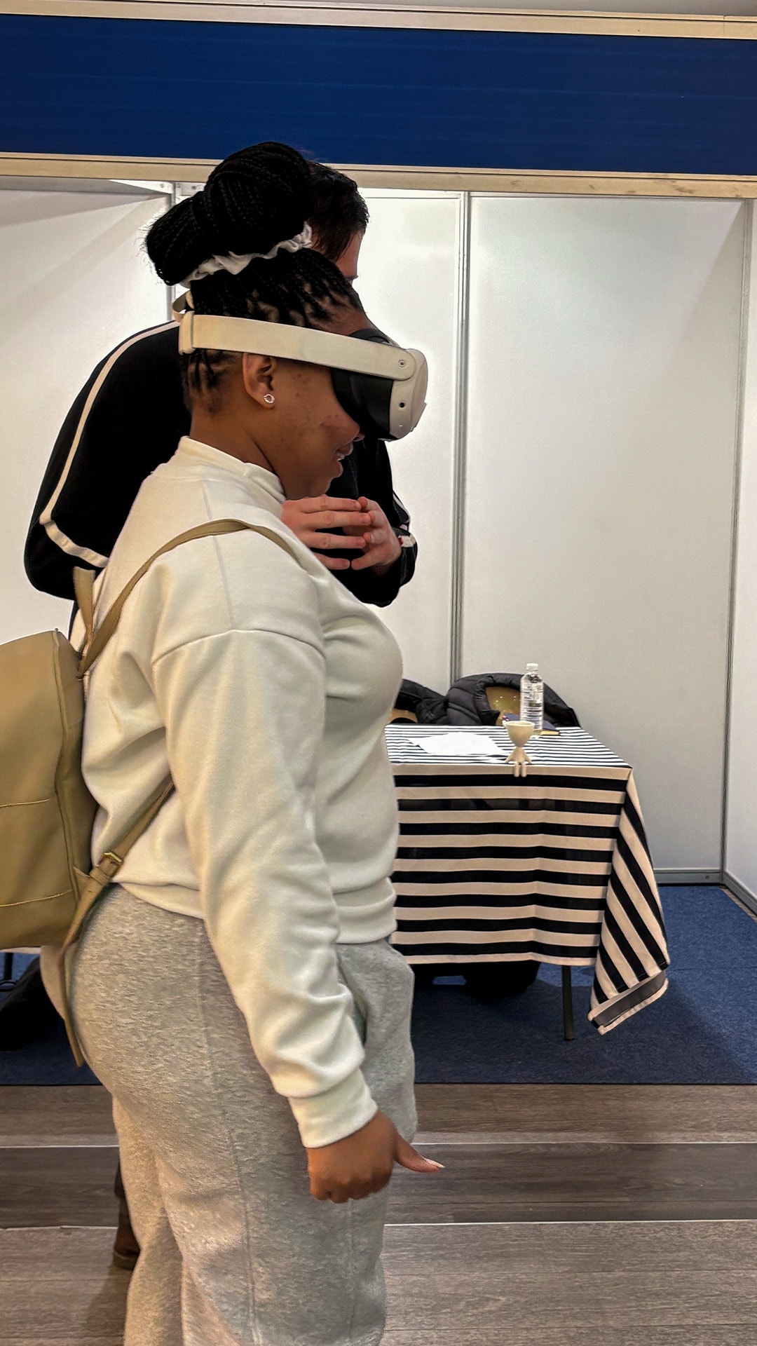 A participant wearing a VR headset beside an event spectator