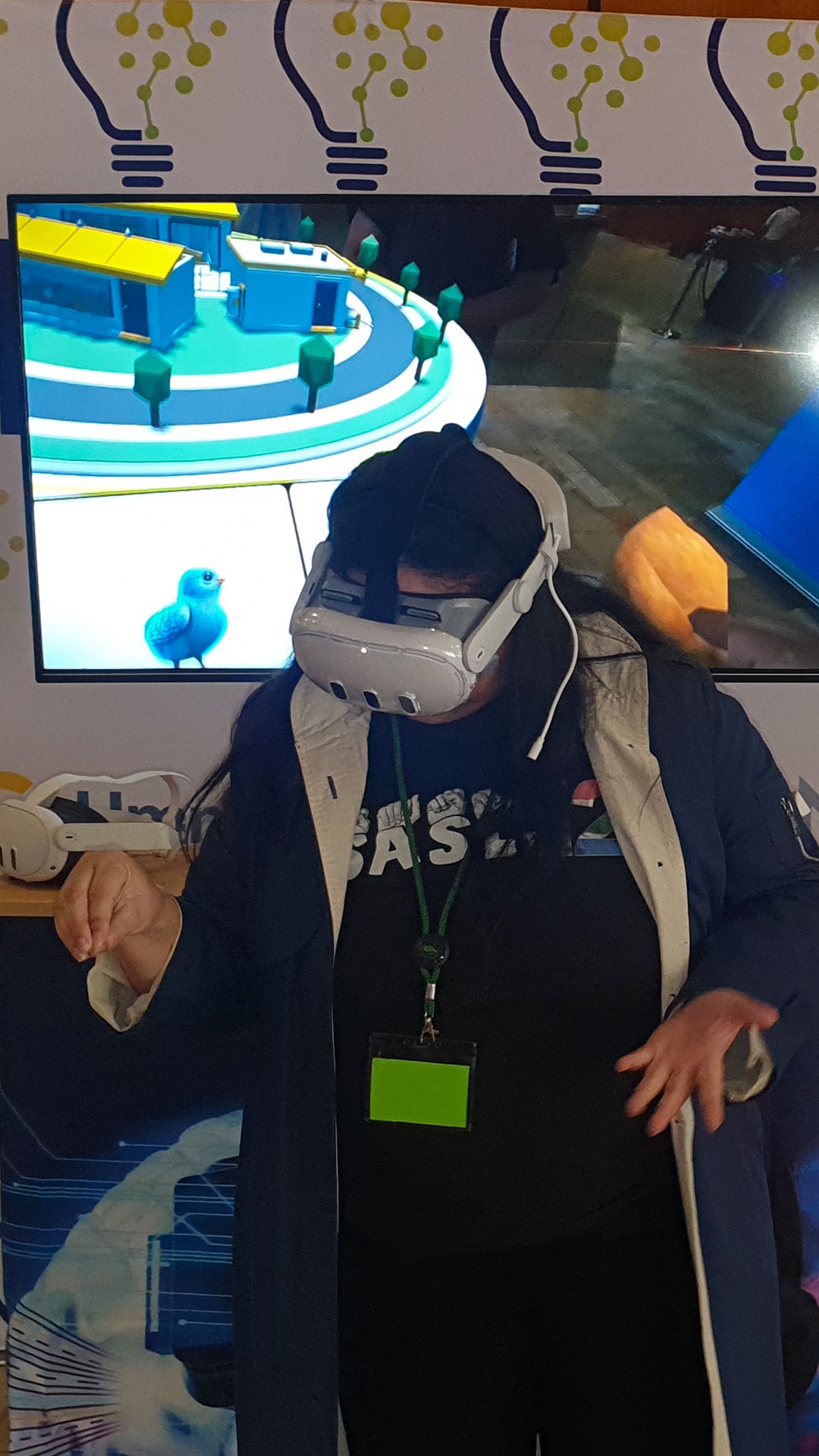 A guest leaning forward with a VR headset and controller beside a game display