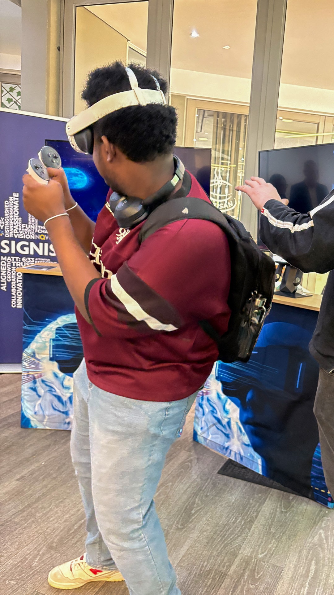 A participant in a red top wearing a headset and holding a VR controller