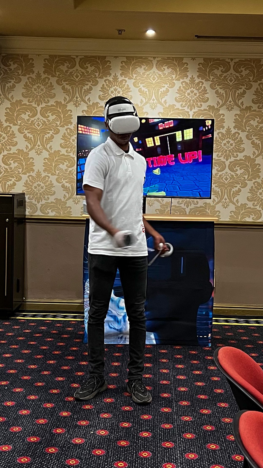 A participant wearing a VR headset beside a spectator screen at a conference