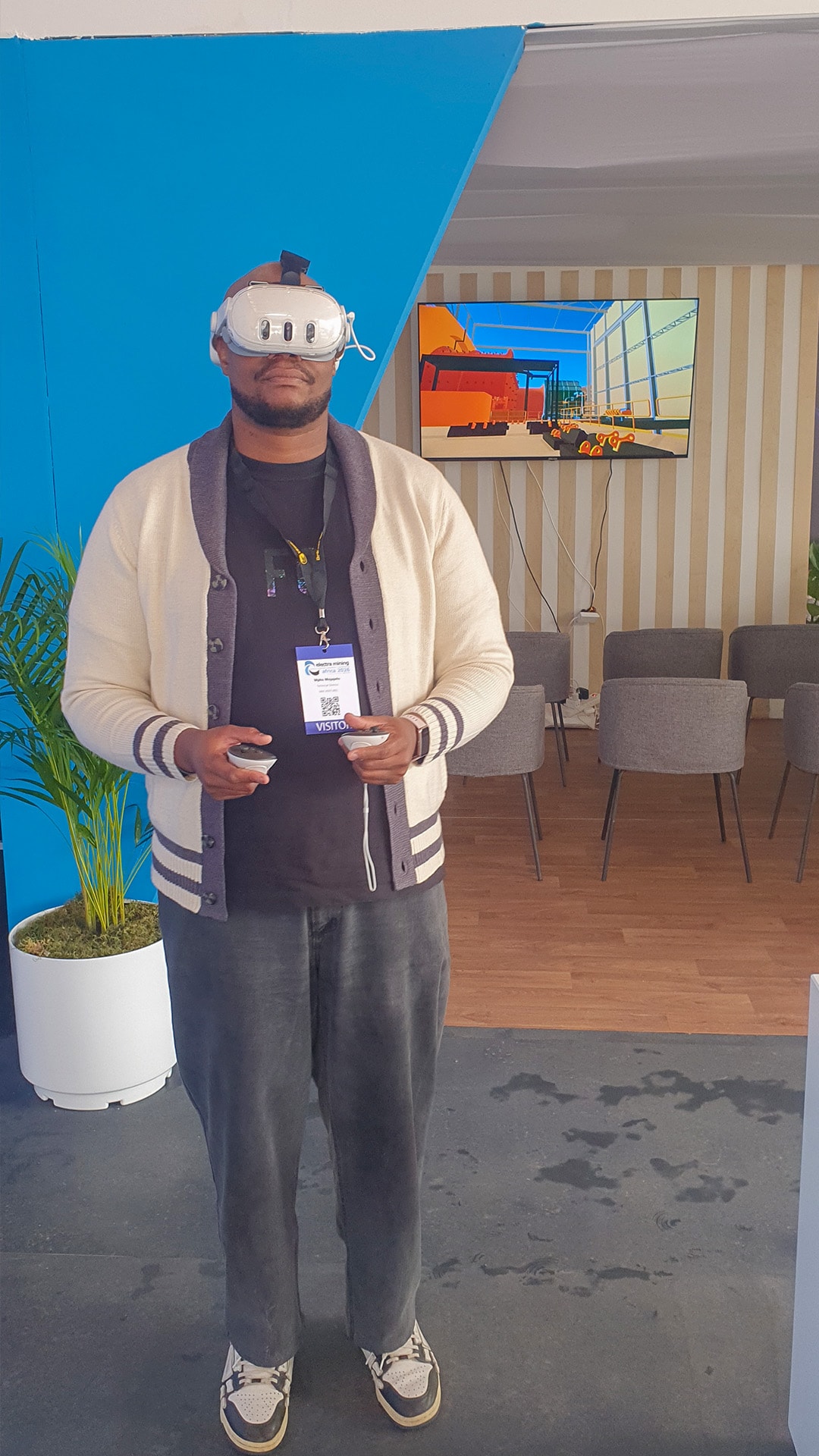 A guest holding VR controllers at a blue exhibition stand