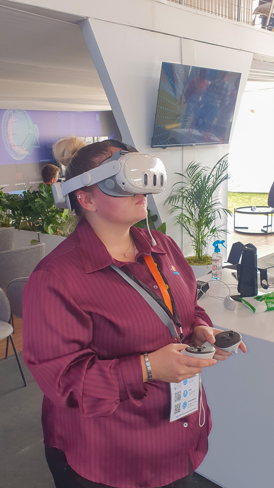 A participant in a burgundy shirt exploring VR with handheld controllers